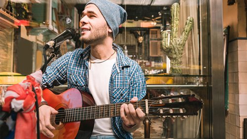 Young man wearing a beanie playing the guitar