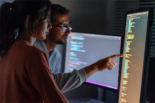 Man and woman looking at a monitor with the lights off