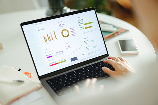 Hands working on a laptop while showing multiple graphs