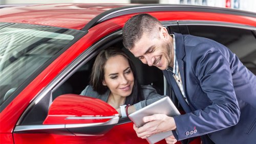 Man showing a woman inside a car a tablet