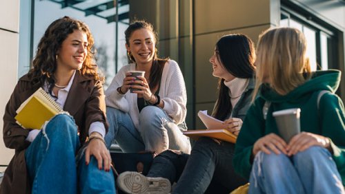Young women sitting and chatting while they hold a coffee in their hands