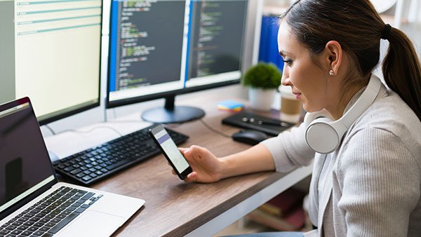 Woman with headphones on the neck holding a phone