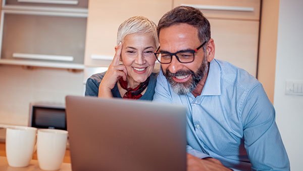 Woman next to a man smiling when seeing something on a camputer screen