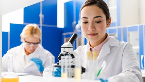 Girl at the lab looking through the microscope